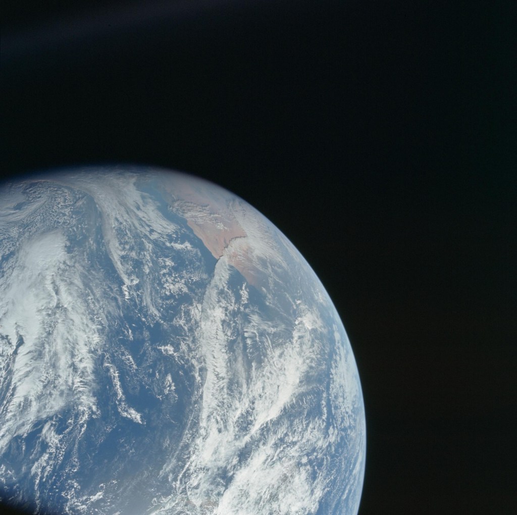 In the bottom left corner, the Earth from space, showing mostly ocean, a little bit of Africa, and swirling clouds.