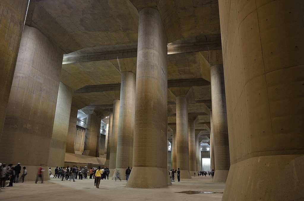 Vast chamber with multiple tall columns, dwarfing human visitors.